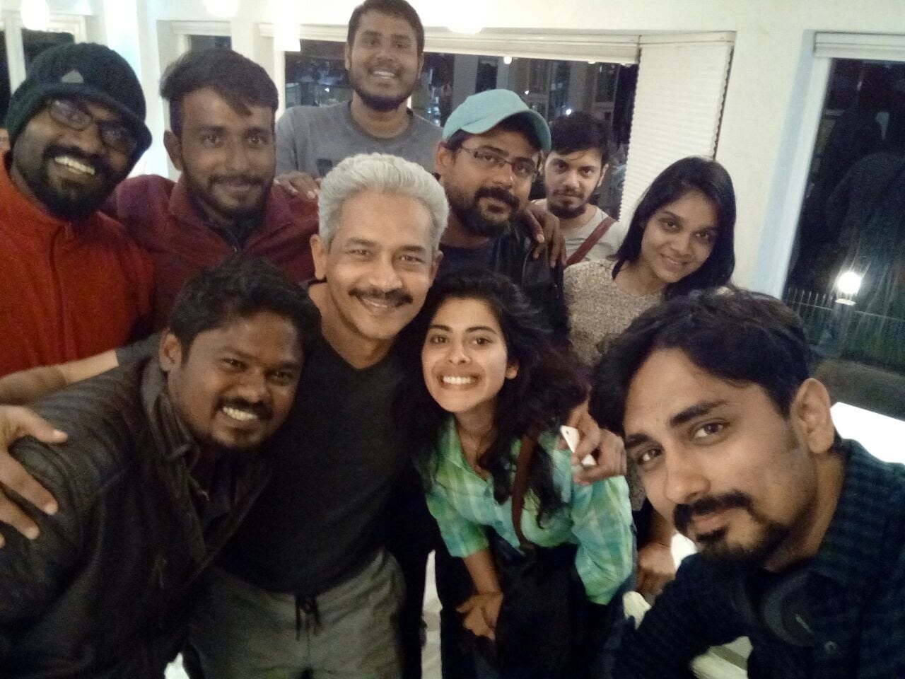 Cast and crew crowded together for a photograph between takes